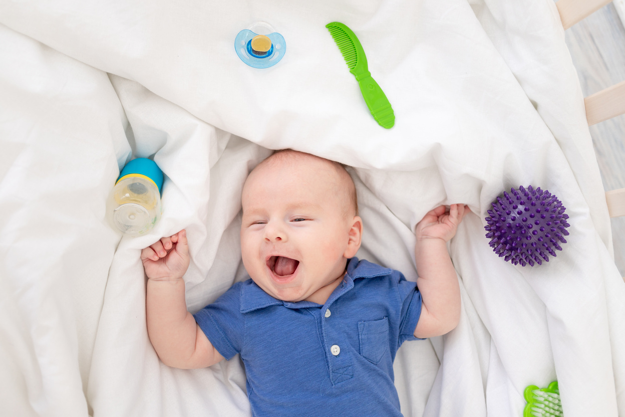 baby boy in a crib among baby supplies, baby products concept